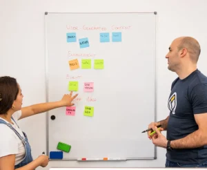 Two people planning a product on a whiteboard covered in sticky notes