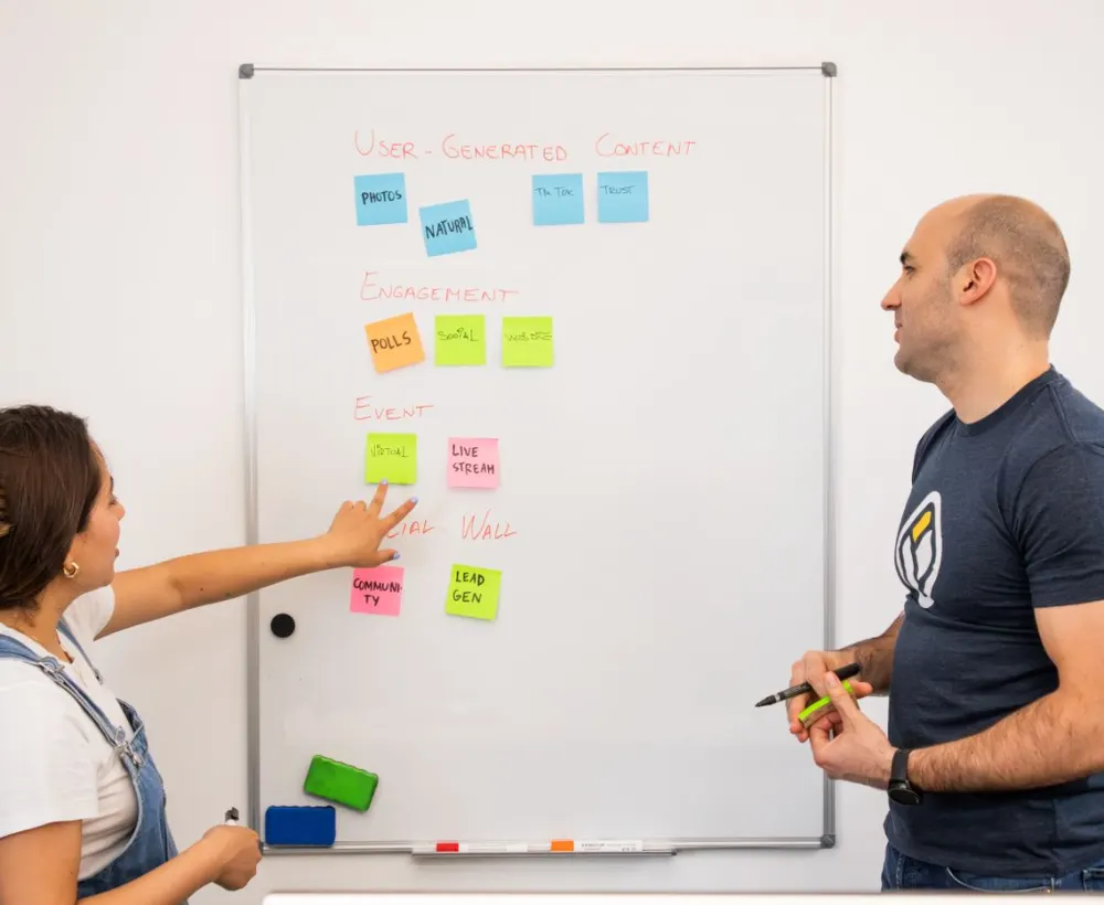 Two people planning a product on a whiteboard covered in sticky notes