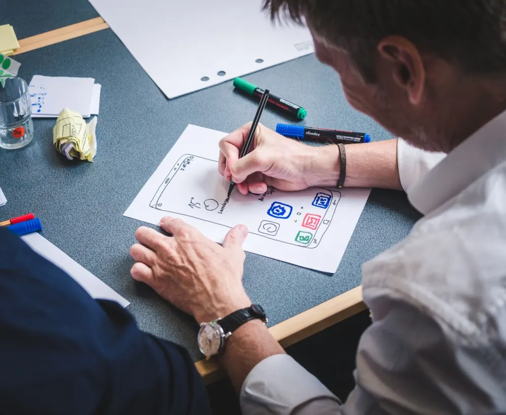 A designer sketching mobile app screens on paper