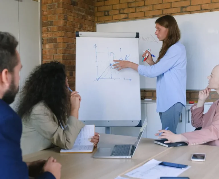 A presenter explaining a chart on a flip chart to colleagues in a meeting room