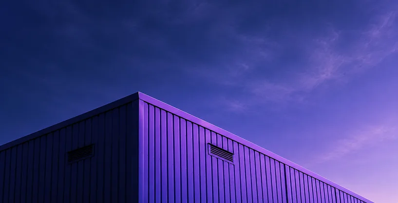 A modern industrial building at dusk under a purple sky