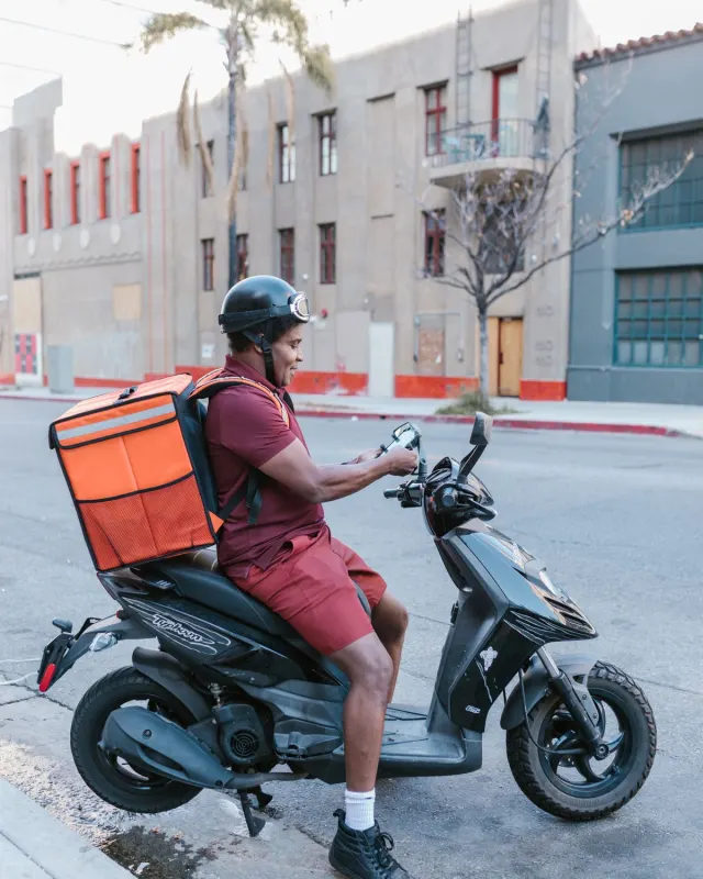 A delivery rider on a scooter in a city street